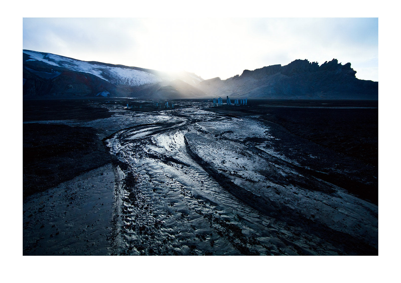 Ice melt forms streams that carve through black volcanic sand beaches. Whalers Bay, Port Foster, Deception Island, South Shetland Islands, Antarctic Peninsula, Antarctica.