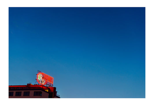 A neon billboard illuminated beneath the summer night sky in Copenhagen. Copenhagen, Denmark.