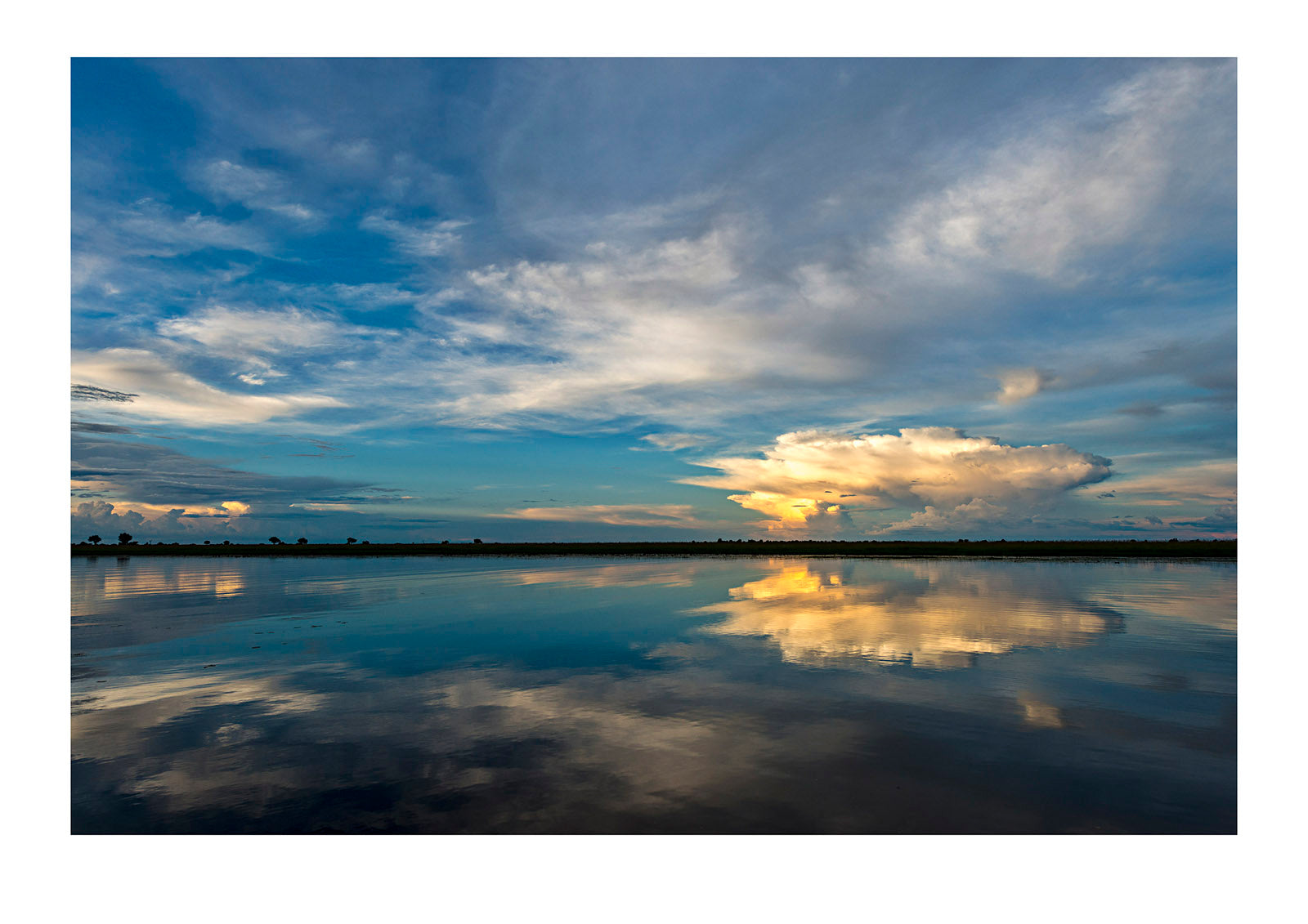 Sunset on the Angolan border and all is quiet. The occasional flash of lightning strikes the floodplain followed by baboon shrieks in the distance. The world falls asleep. Angola.