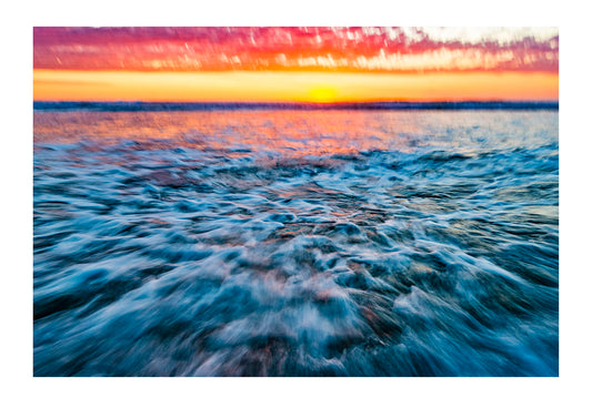 The blur of waves rushing onto a beach on an incoming tide at sunset. Venus Bay, Victoria, Australia.