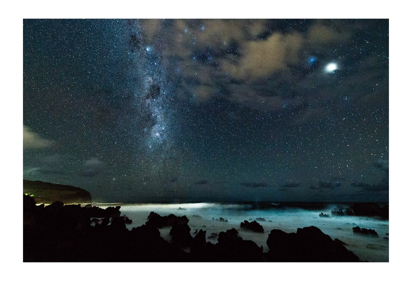 The Milky Way Galaxy rises over a volcanic coastline on the Pacific Ocean. Hanga Roa Eco Village, Rapa Nui, Easter Island, Chile