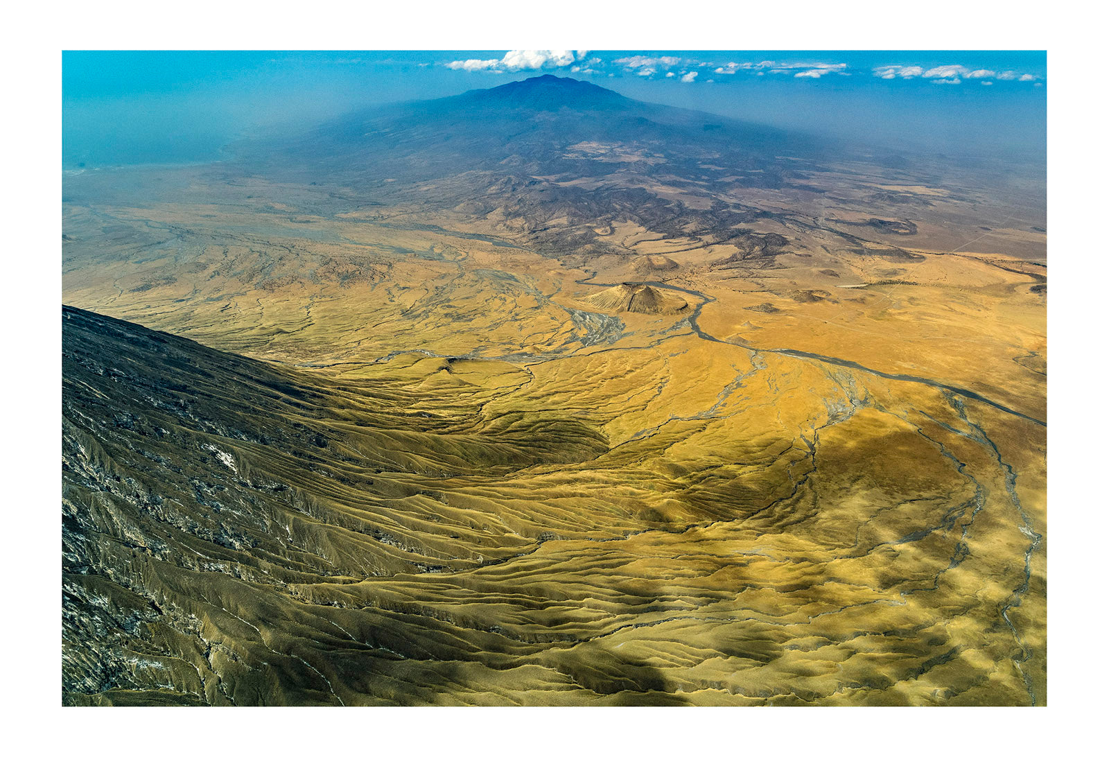 An aerial view of grass covered lava flows descending the slopes of an active volcano. Crater Highlands, Ngorongoro Hig, African Rift Valley , Serengeti National Park, Tanzania