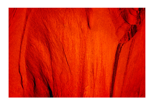 Sunset falls across rusty waves of sandstone on the Uluru formation. Uluru National Park, Northern Territory, Australia.