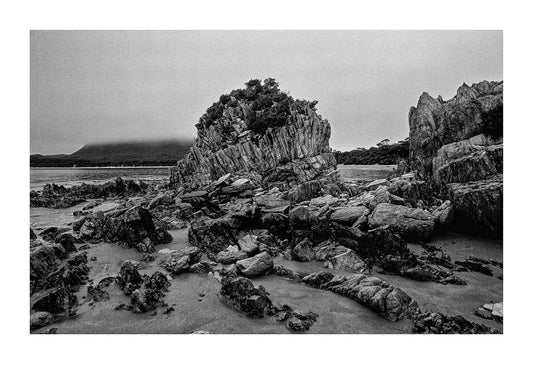 Stormy skies over a granite outcrop exposed at low tide. South West National Park, Tasmanian Wilderness World Heritage Area, Tasmania, Australia.